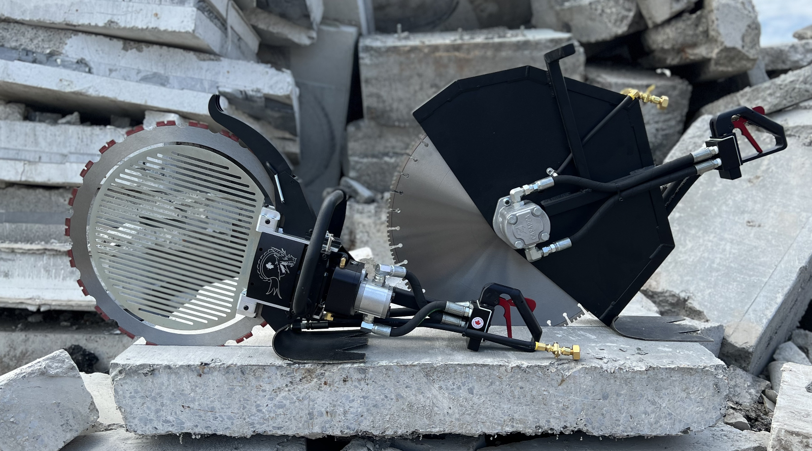 Two hydraulic concrete saws resting on a broken slab, with stacked concrete debris in the background
